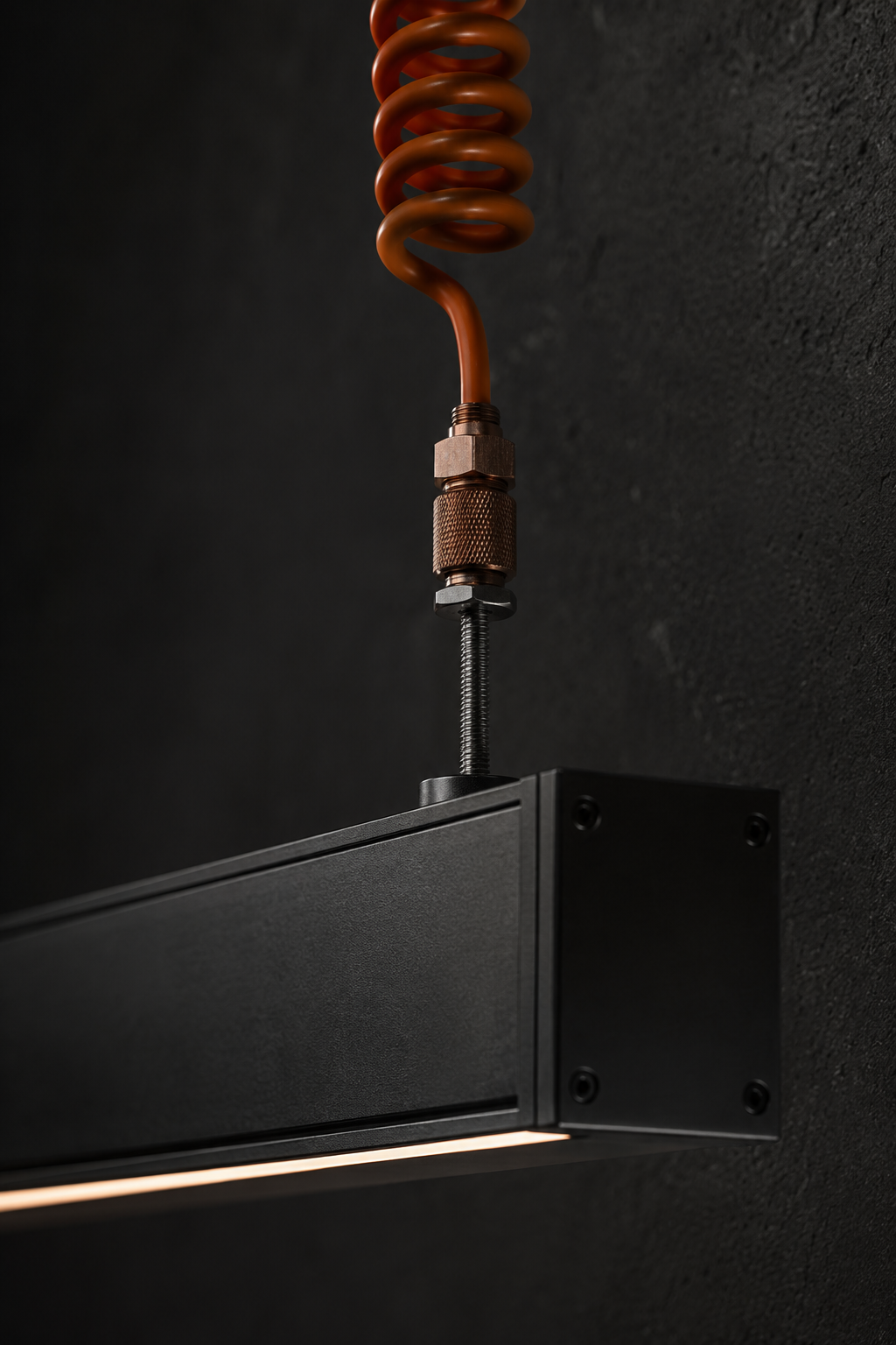 Suspension detail showing threaded rod, bronze coupler, and coiled conduit on a matte black extrusion